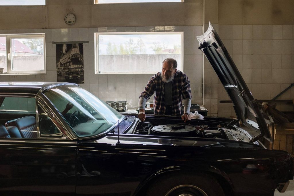 man repairing classic black car